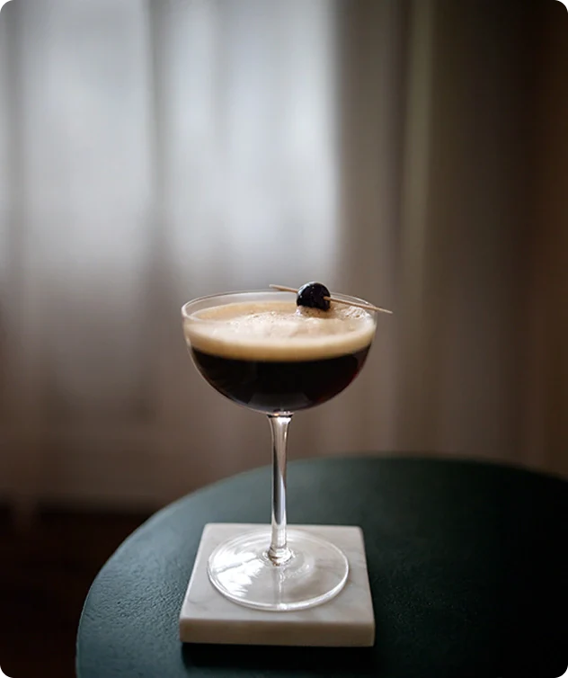 Cocktail in a glass with a dark liquid and foam on a blurred background