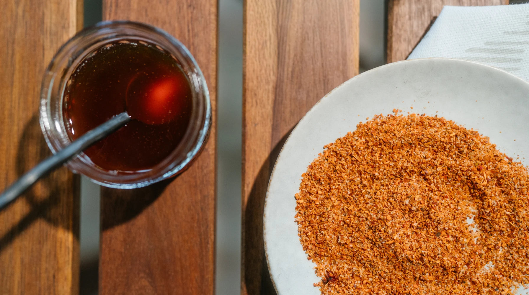 Hot Honey Coffee Lemonade with a spoon and plate of chili lime seasoning on a wooden surface.