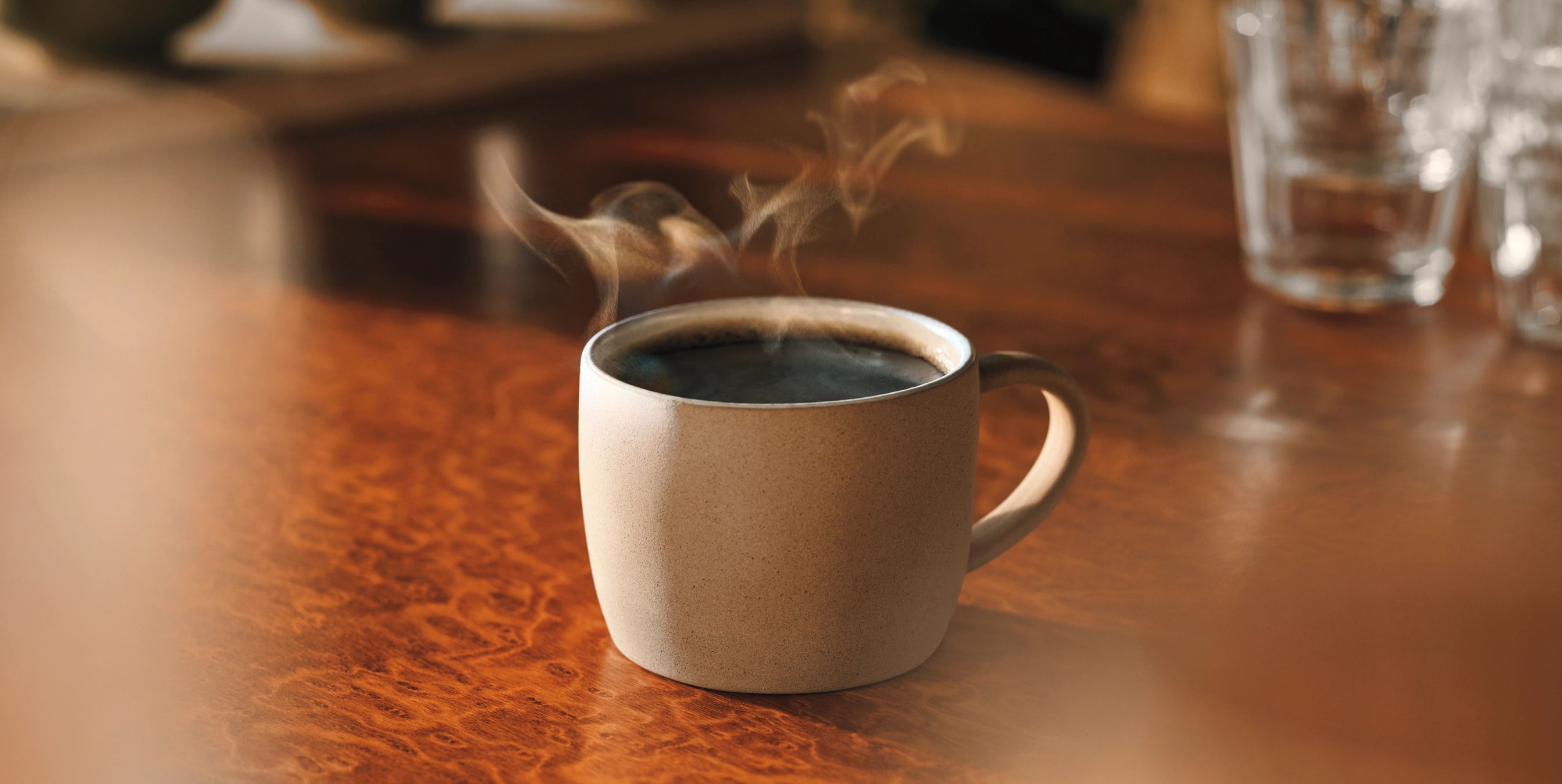 Steaming coffee cup on a wooden table with blurred background