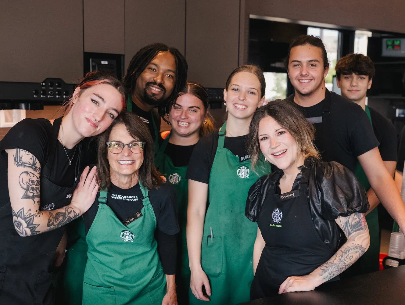 Group of Starbucks employees posing together in a kitchen setting.
