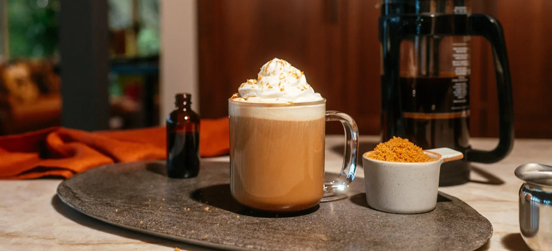 Hot Roasted Crème Brûlée with whipped cream on a wooden table with coffee beans and a coffee machine in the background.