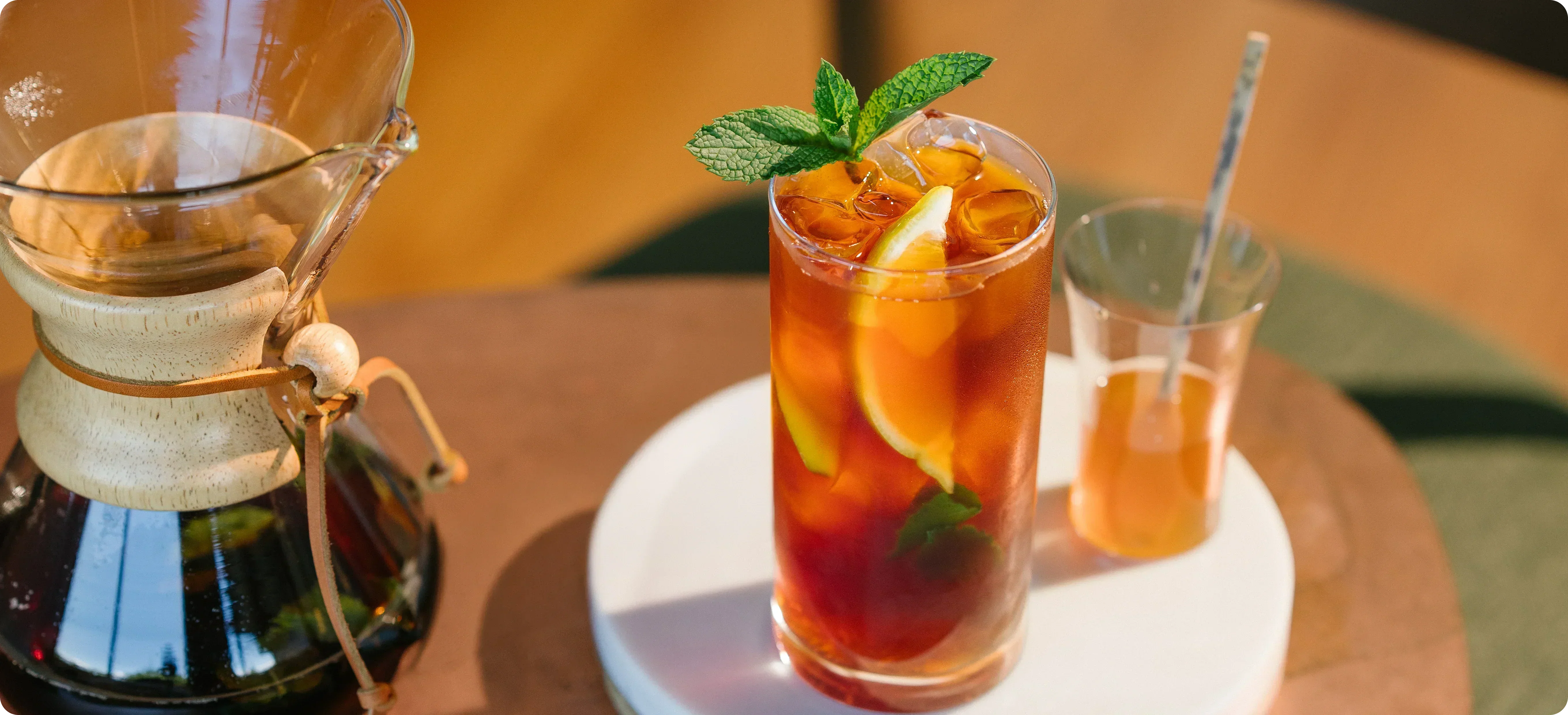 Pour-over coffee maker with iced tea and lemon slices on a wooden table