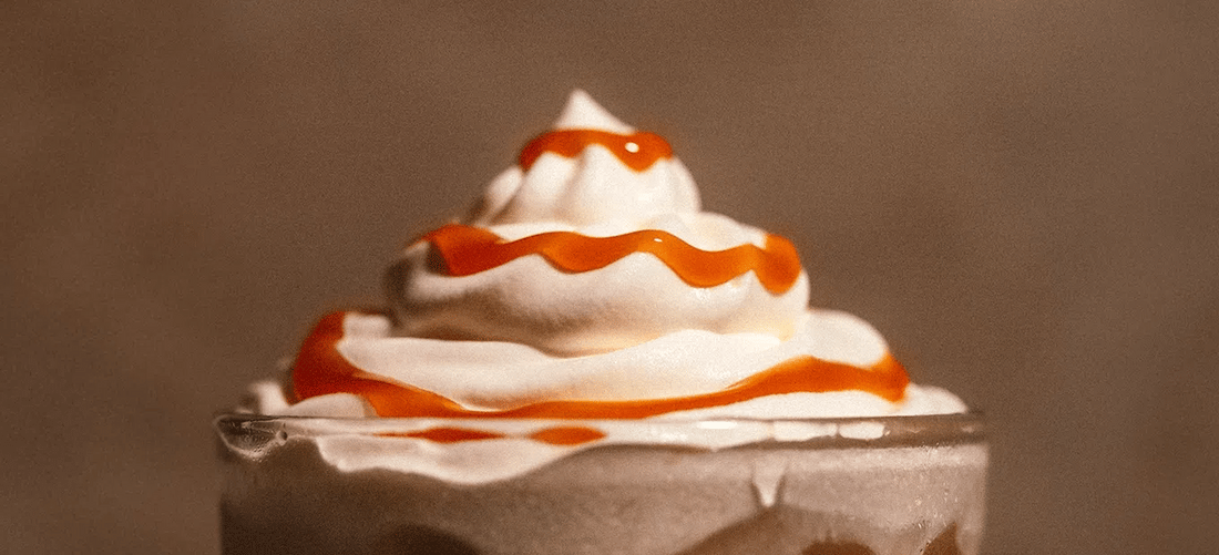 Glass of Salted Caramel Cold Brew with whipped cream and caramel drizzle.