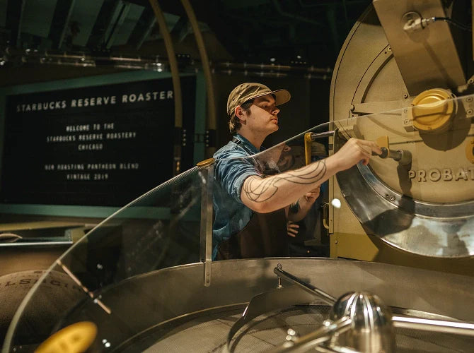 A person operating a large coffee roasting machine in a Starbucks Reserve Roastery.