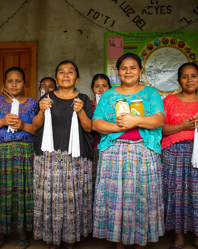 A group of women holding their candles as part of their candle-making business.