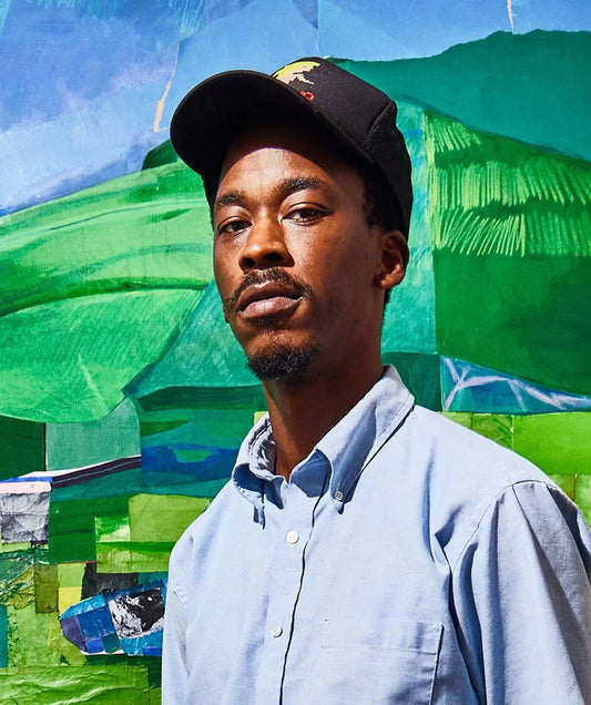 The artist, Hampton Boyer, wearing a cap and standing in front of his colourful abstract artwork.
