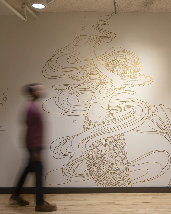 A person walking past a wall with a large, detailed Art Deco illustration artwork by Marcos Chin.
