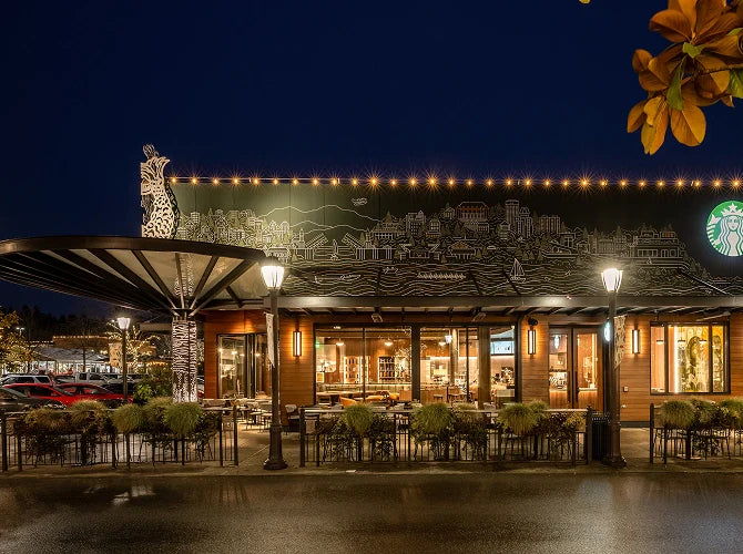 Exterior of Starbucks' University Village coffeehouse in Seattle at night, with illuminated sign and decorative elements.