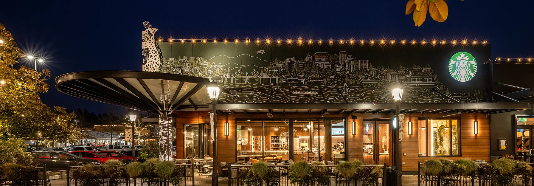 Exterior of Starbucks' University Village coffeehouse in Seattle at night, with illuminated sign and decorative elements.