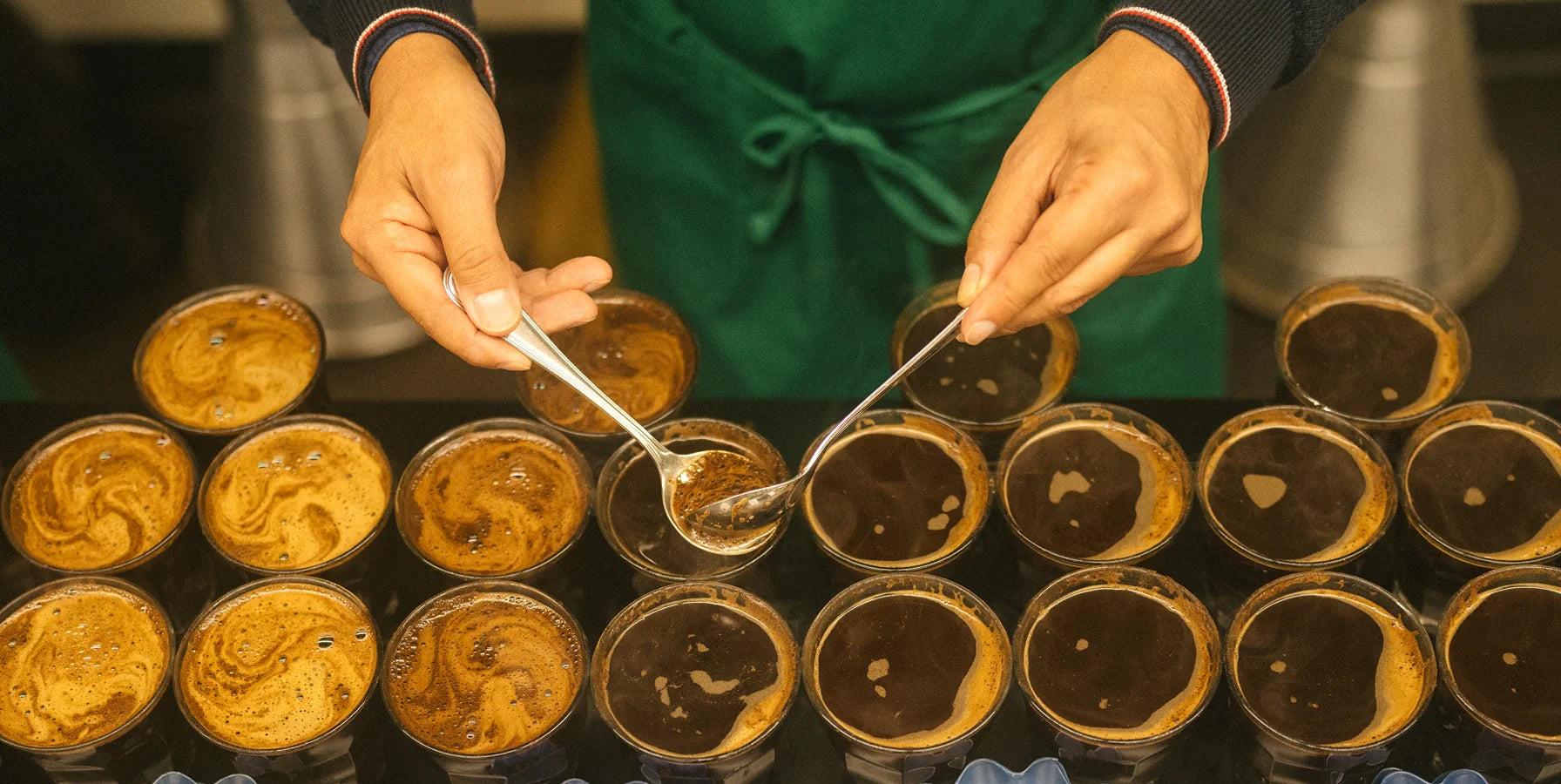 A team member scoping up to check the quality of coffee within each cup.