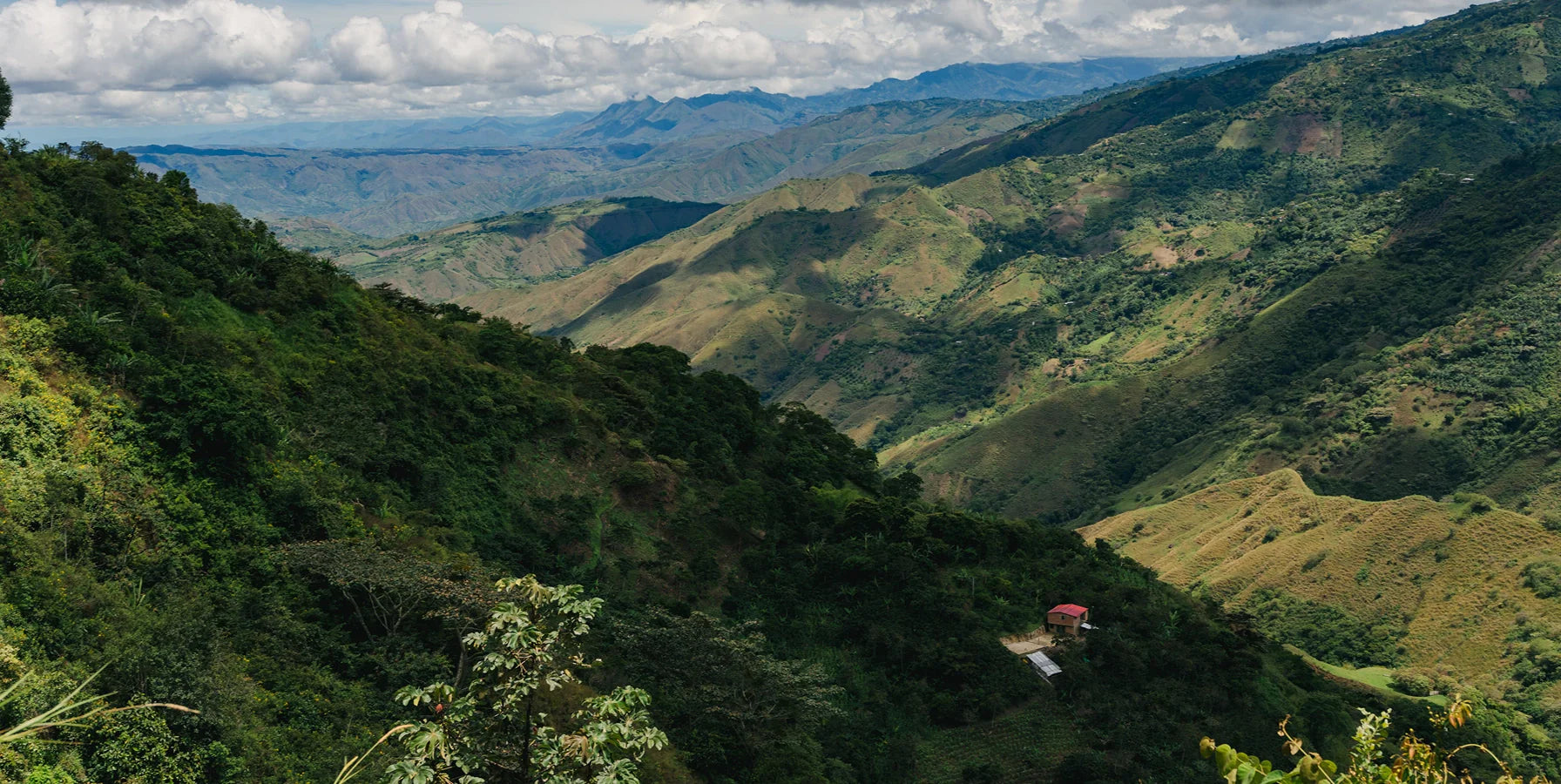 Scenic view of lush green mountains under a partly cloudy sky.