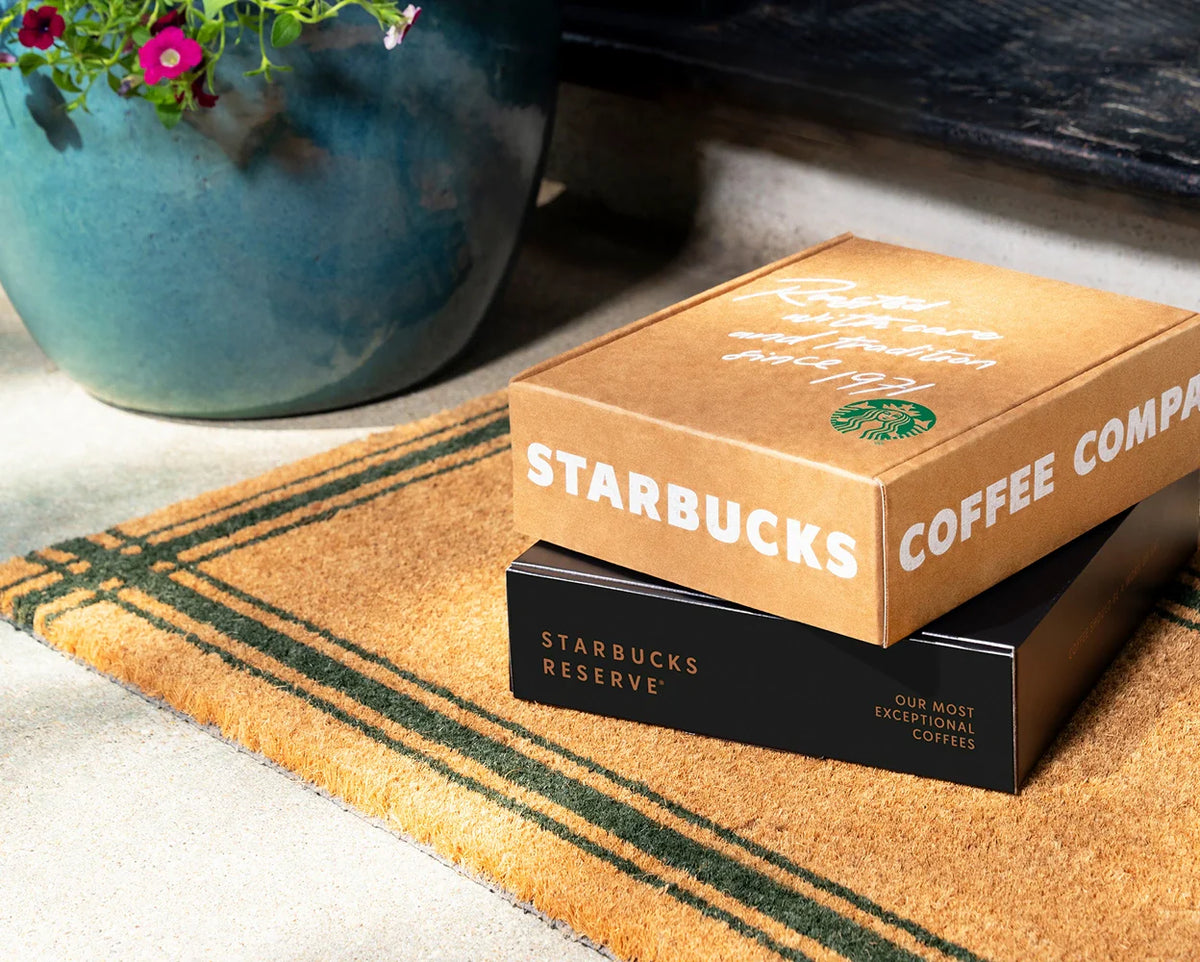 Two Starbucks Subscription boxes, with the one below that says Starbucks Reserve, stacked on top of each other in front of the doorstep.