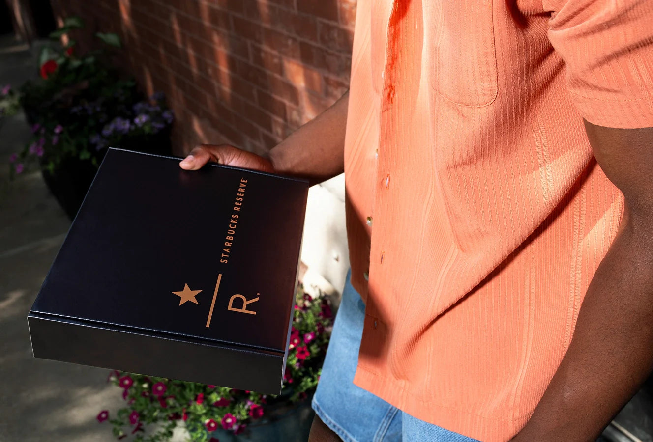 Person holding a black Starbucks Reserve coffee box outdoors.