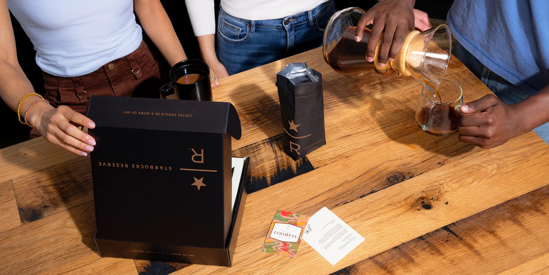 People around a wooden table with a Rượu Vang Noir box, bottle, and glass.