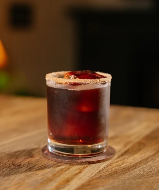 Glass of Iced Coffee Apple Pie with a sugared rim on a wooden surface, blurred background.