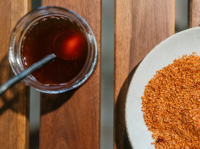 Hot Honey Coffee Lemonade with a spoon and plate of chili lime seasoning on a wooden surface.