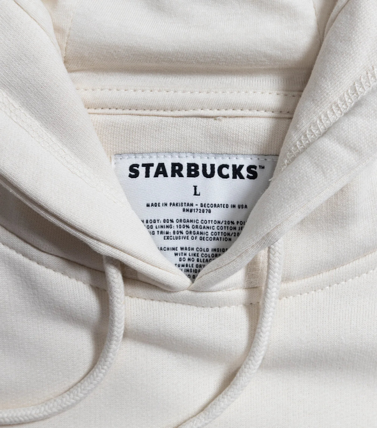 Close-up of a hoodie label that says Starbucks and L size on it, with additional clothing material details.