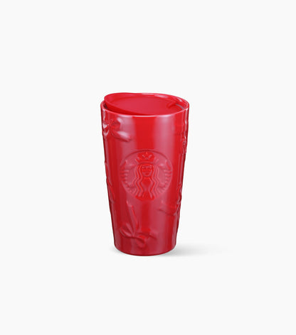 A red Starbucks ceramic tumbler with a textured, embossed bow pattern and the embossed Starbucks siren logo on the front, shown on a clean white background.
