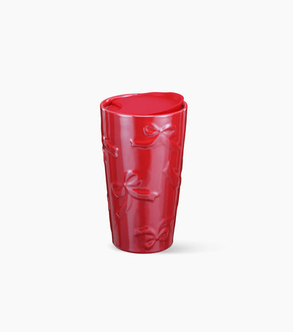 A glossy red ceramic tumbler with embossed bow patterns, shown on a clean white background.