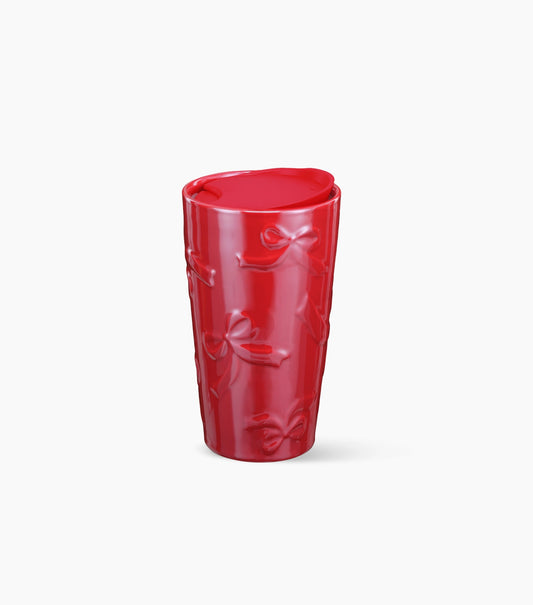 A glossy red ceramic tumbler with embossed bow patterns, shown on a clean white background.
