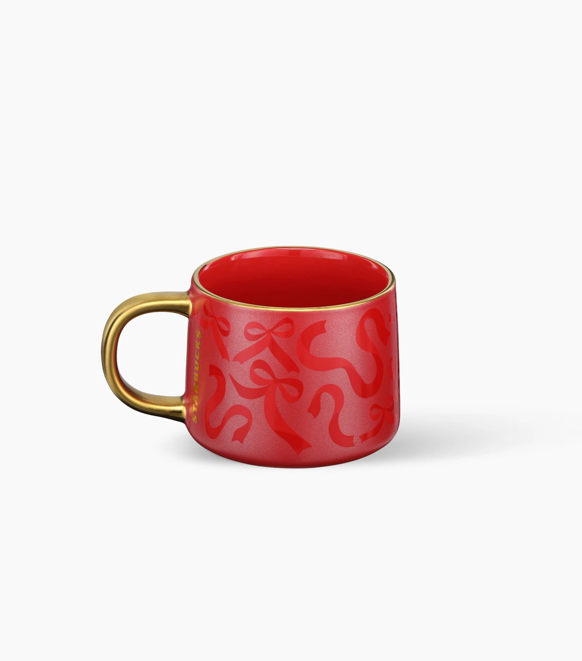 A red ceramic mug with a red ribbon and bow pattern, a gold rim and a gold handle, shown on a clean white background.