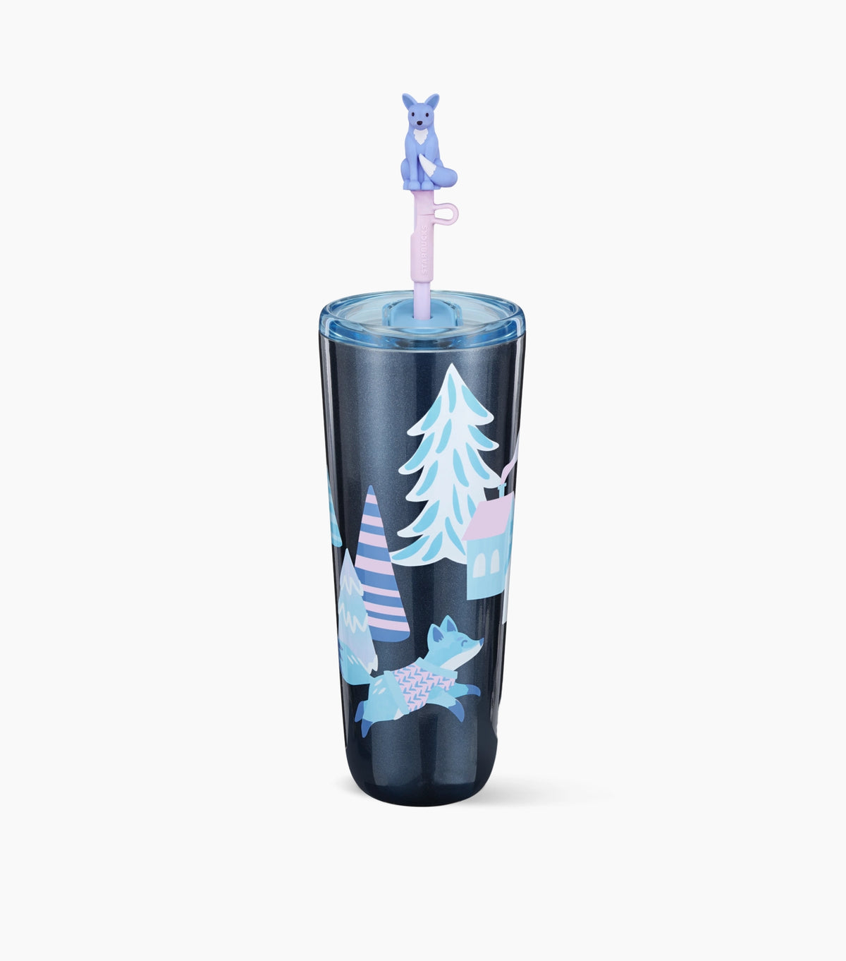A tall insulated tumbler with a clear lid and straw, featuring a winter forest illustration in light blue, white, and pink on a dark navy base. A small blue fox figurine sits on top of the straw.