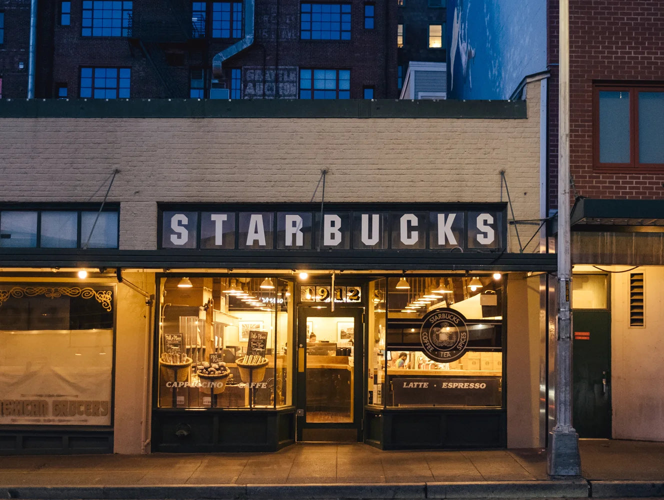 Starbucks store front at night with illuminated sign and interior lights.