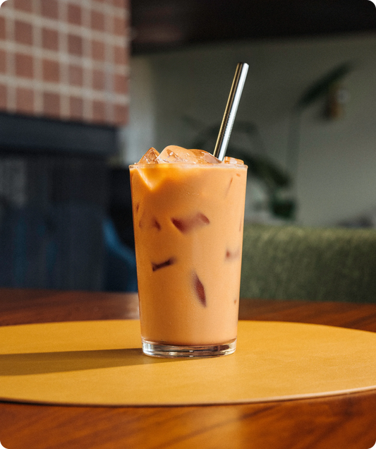 Iced coffee with a straw in a glass on a wooden table
