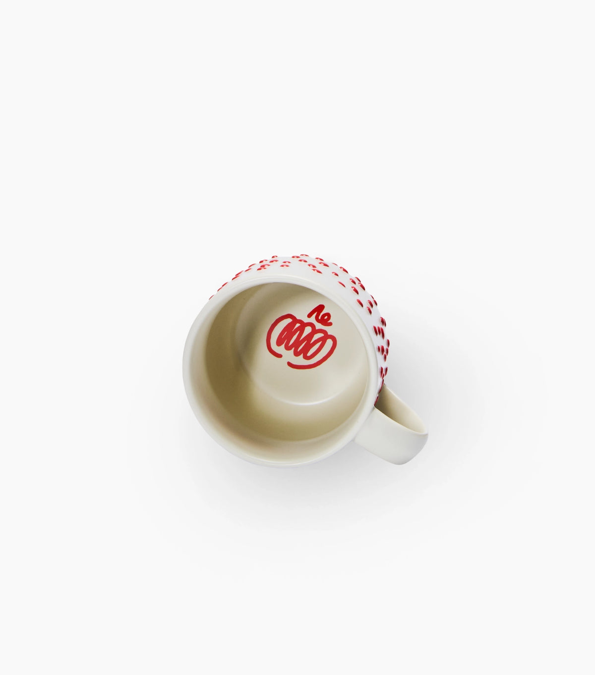 A white ceramic coffee mug viewed from above, featuring a red patterned rim and a red stylized pumpkin printed inside the cup.