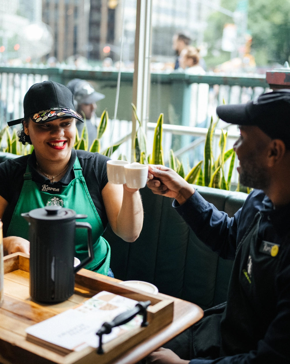 Two Starbucks employees doing a cheers