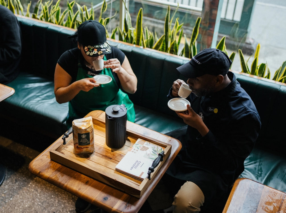 Two Starbucks employees tasting coffee