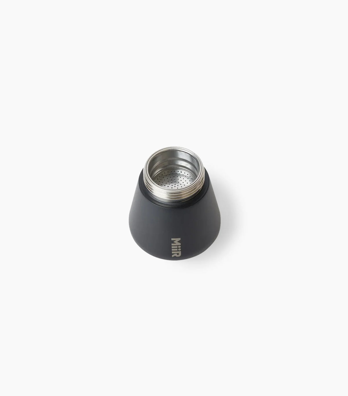 Filter basket of a black Miir Moka Pot Espresso Maker, sitting on top of the bottom chamber, against a white background.