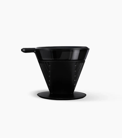 Black plastic Starbucks Pour-Over Brewer with handle towards the left, on a white background.