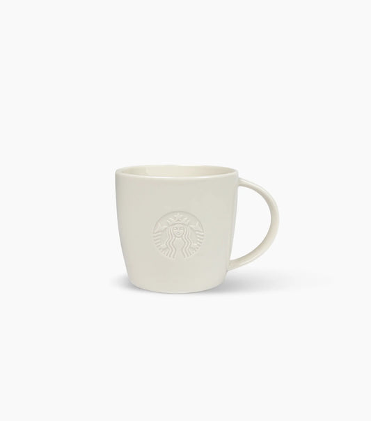 A minimalist ceramic coffee mug in a warm off-white or cream color, featuring an embossed Starbucks siren logo on the front, set against a solid white background.