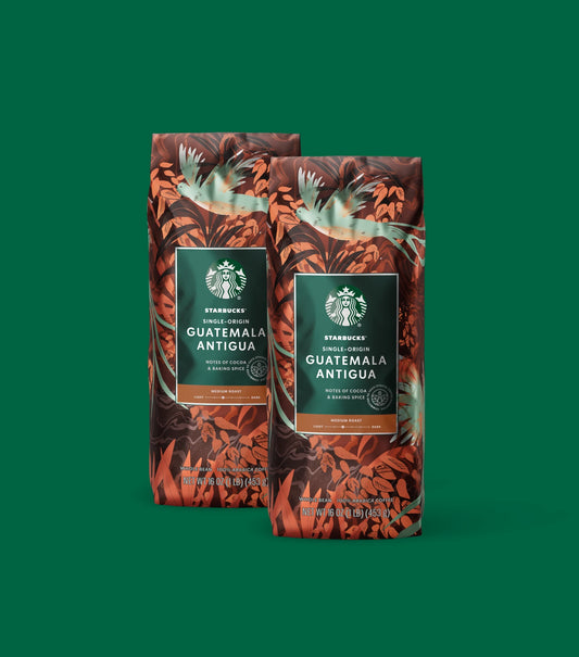 Two Starbucks Single-Origin Guatemala Antigua coffee bags on a green background.