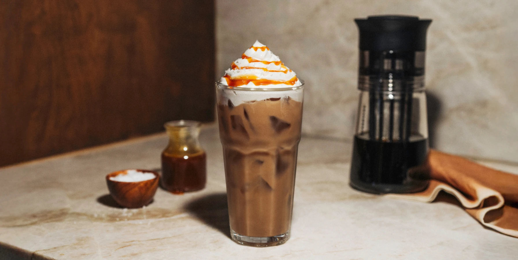 Glass of Salted Caramel Cold Brew with whipped cream and caramel drizzle.