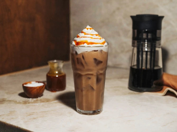 Glass of Salted Caramel Cold Brew with whipped cream and caramel drizzle.