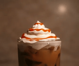 Glass of Salted Caramel Cold Brew with whipped cream and caramel drizzle on a brown background.