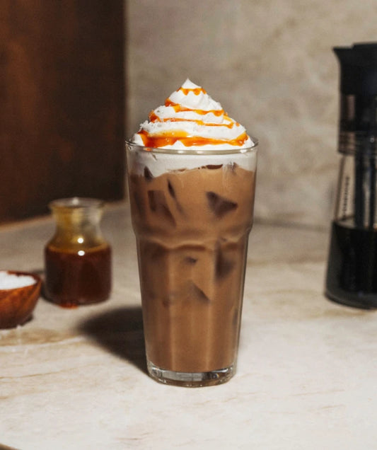 Glass of Salted Caramel Cold Brew with whipped cream and caramel drizzle.