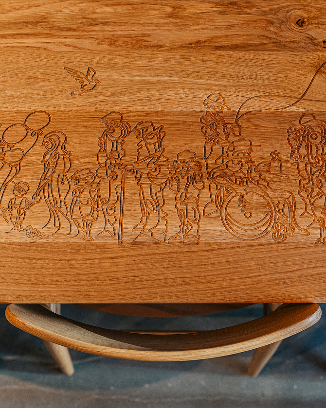 Wooden table at a Starbucks coffeehouse, with intricate carvings of people and animal figures on the surface.
