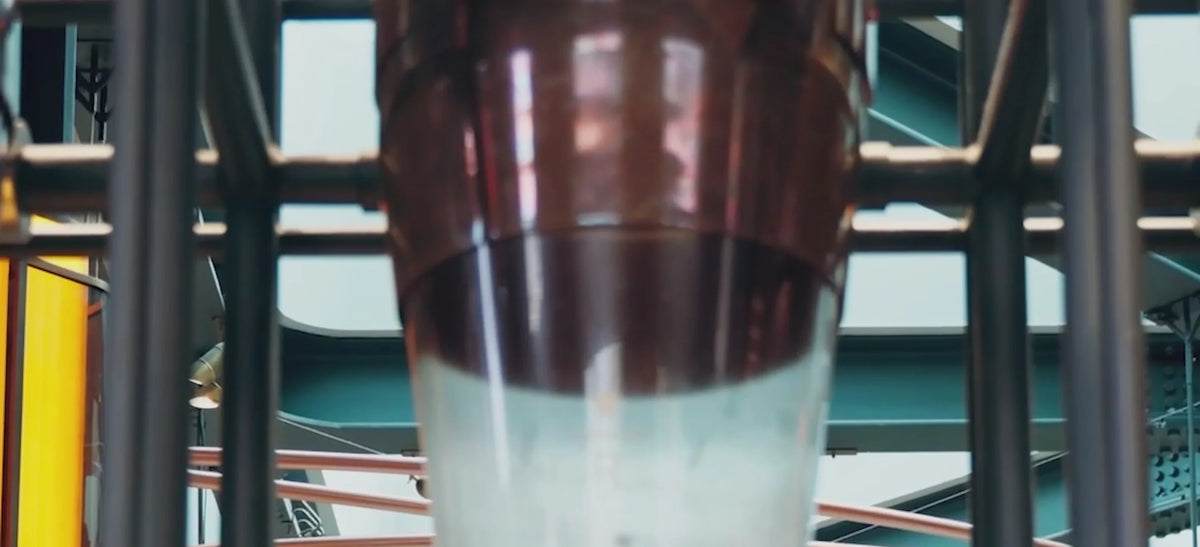 Video showing a coffee grinder is slowly filled with Starbucks Reserve coffee beans. Coffee beans pour out of a container. Starbucks employees monitor the production process. Coffee beans circulate in a giant roaster. A Starbucks Master Roaster performs quality control on the beans. Coffee packages are sealed and transported on belts. The inside of the Milano Starbucks Reserve Roastery is shown, featuring counters full of pastries, coffee bean dispensers, and a Starbucks barista placing a coffee cup on the counter.