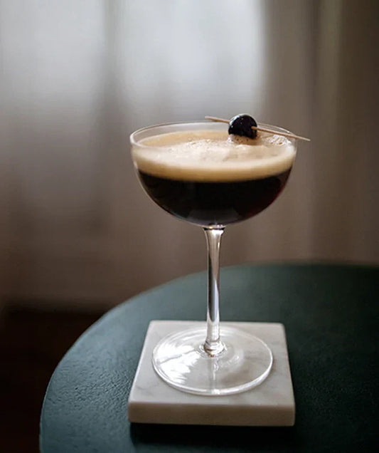 Cold brew lemon sour in a cocktail glass, with an olive on top.