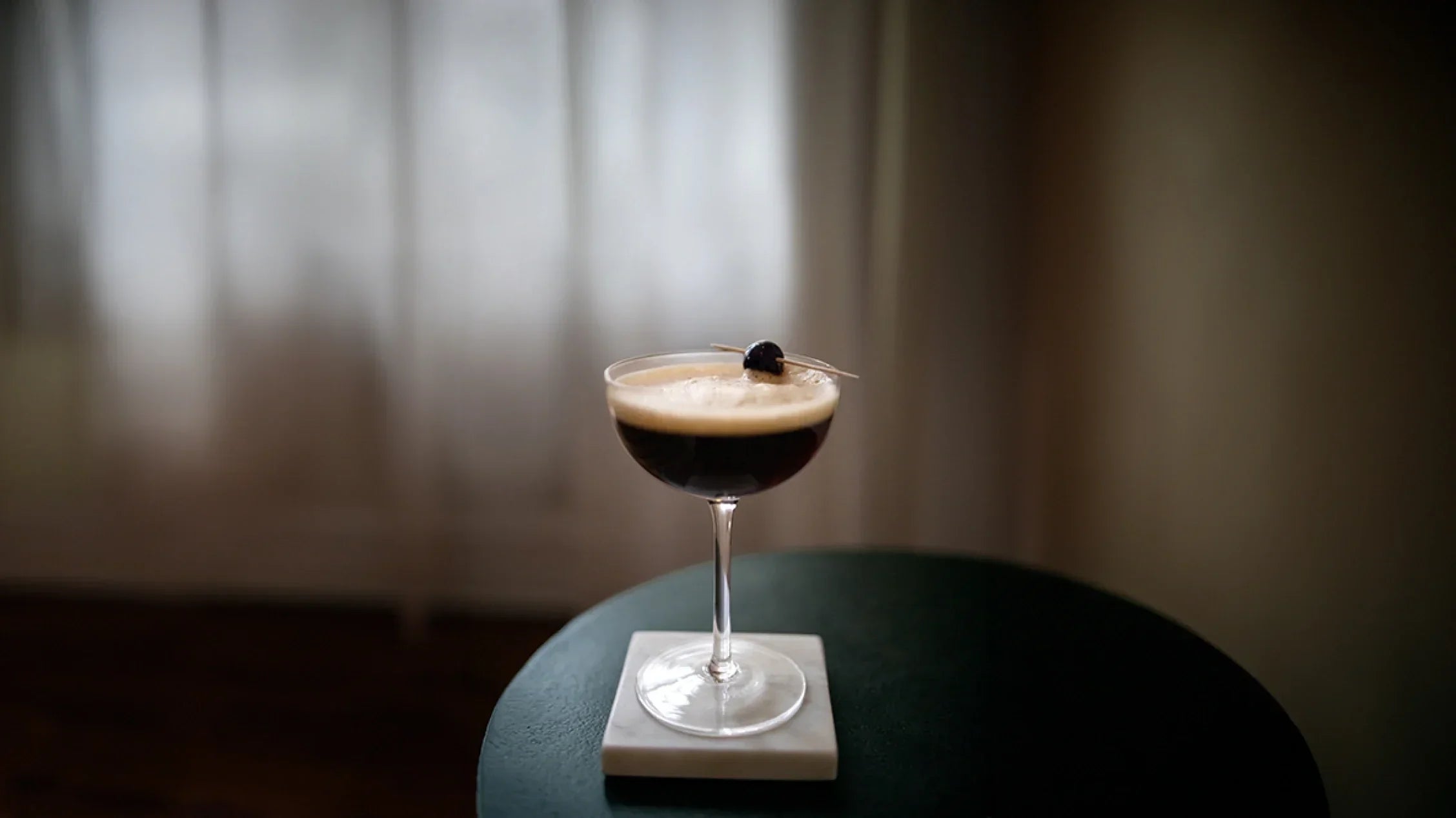 Cocktail in a glass with a dark liquid on a blurred background