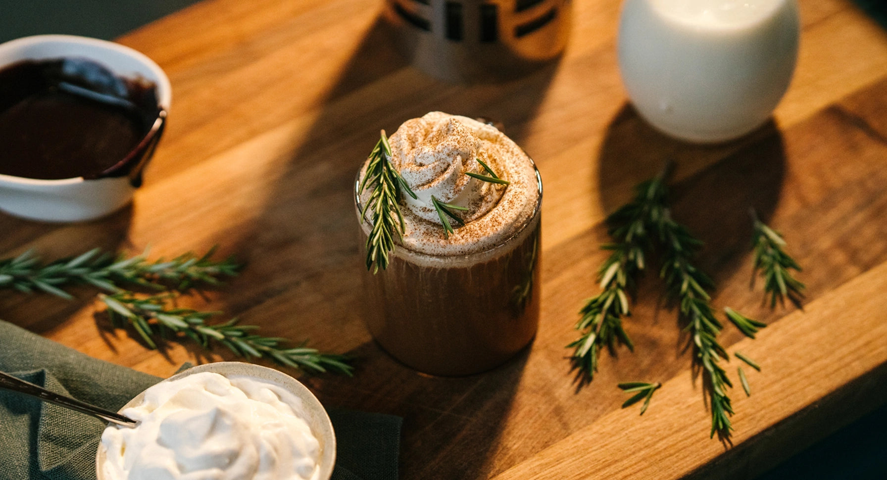 Hot chocolate with whipped cream and rosemary on a wooden surface