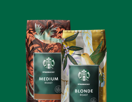 Two bags of Starbucks coffee - the one on the left is Starbucks Medium Roast, and on the right, Starbucks Blonde Roast, both against a green background.